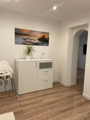 une cuisine avec des placards blancs et un tableau mural. dans l'établissement Ferienwohnung Wasserkunst, à Bad Harzburg