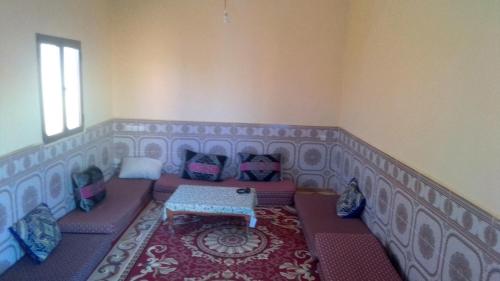 een kamer met een bank met kussens en een tafel bij Obira Oasis Merzouga Camp in Merzouga