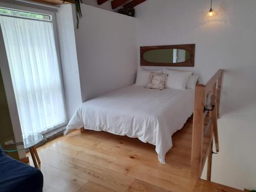 1 dormitorio con 1 cama con sábanas blancas y espejo en VIVIENDA VACACIONAL LA CASINA en Barro de Llanes