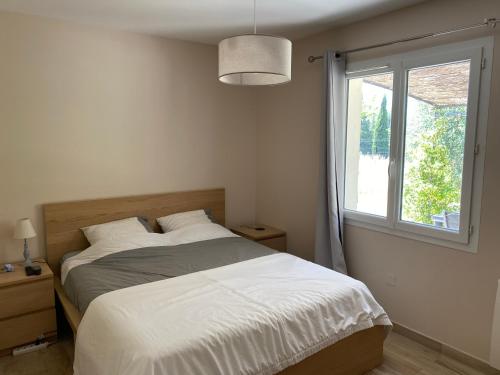 a bedroom with a large bed and a window at Maison de plain pied avec terrain de pétanque in Draguignan