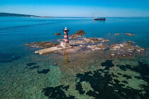 a lighthouse on a small island in the water at Moon's Tower suite&rooms in Portoscuso