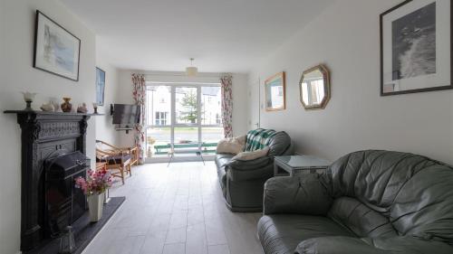 Strand Cottages Ballycastle Seafront في باليكاسل: غرفة معيشة مع أريكة ومدفأة