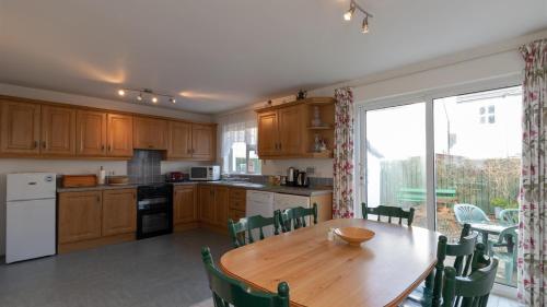 a kitchen with a wooden table and a large window at Strand Cottages Ballycastle Seafront in Ballycastle