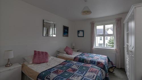 a bedroom with two beds and a window at Strand Cottages Ballycastle Seafront in Ballycastle