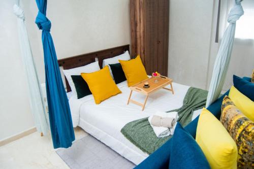 een bed met gele en groene kussens en een tafel bij Studio Cozy Parc Mohammedia in Mohammedia