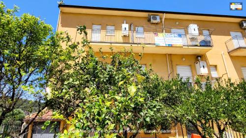 a yellow building with balconies and trees in front of it at Scala dei Turchi Apartment in Realmonte