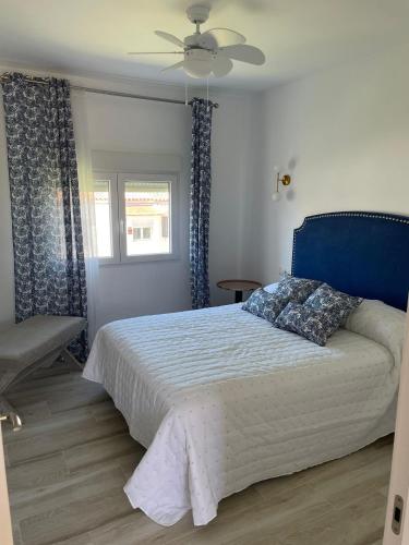 a bedroom with a bed with a blue headboard and a window at Relax y sol in Torreguadiaro