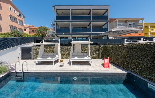 una piscina con 2 sillas y una mesa junto a un edificio en Villa Twins, en Crikvenica