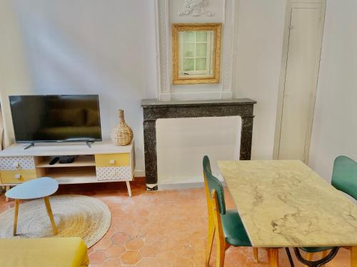 - un salon avec une table, une télévision et une cheminée dans l'établissement La Suite du Castillet, à Perpignan