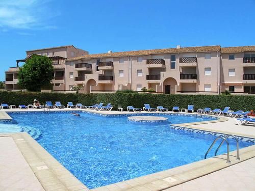 une grande piscine avec des chaises et un bâtiment dans l'établissement Amiraute Apartment J9, à Saint Cyprien Plage