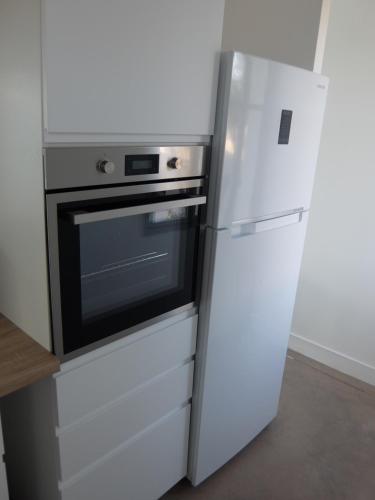 une cuisine avec un réfrigérateur et un micro-ondes dans l'établissement Superbe appartement proche des plages avec parking gratuit, à Ramatuelle