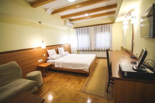 a bedroom with a bed and a couch and a desk at Hotel Vila Vrbas in Banja Luka