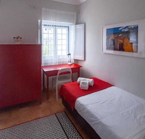 a small bedroom with a bed and a red desk at Casa da Travessa - Óbidos in Óbidos