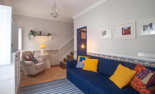 ein blaues Sofa mit gelben Kissen im Wohnzimmer in der Unterkunft Casa da Travessa - Óbidos in Óbidos