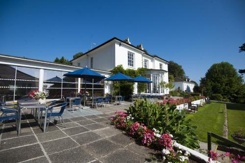 a patio with tables and blue umbrellas in front of a building at Penmere Manor Hotel in Falmouth