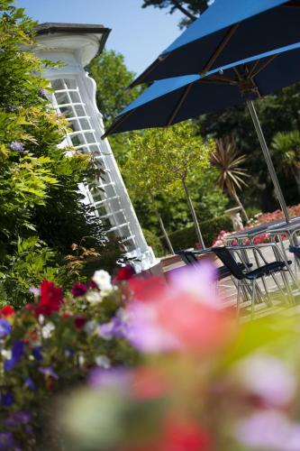 a table with chairs and an umbrella and flowers at Penmere Manor Hotel in Falmouth