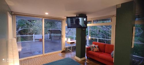 a living room with a red couch and a television on a pole at Green House by W. in Heredia