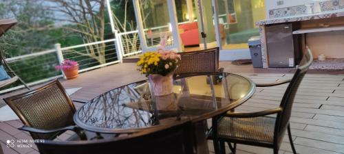 a glass table with a vase of flowers on a porch at Green House by W. in Heredia