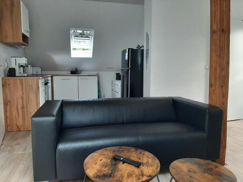 Un sofá de cuero negro y dos mesas en una cocina. en Ferienwohnung Muh - Ostfriesland nähe Nordsee, en Rechtsupweg