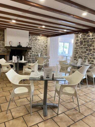 un restaurant avec des tables et des chaises blanches et un mur en pierre dans l'établissement Hôtel-restaurant La bonne hôtesse, à Chambon-sur-Lac