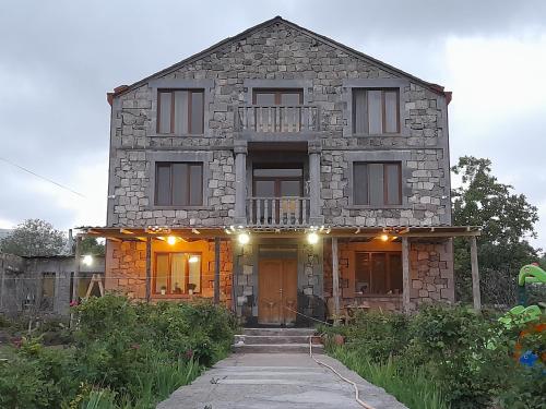 une maison en pierre avec une porte d'entrée et une terrasse couverte dans l'établissement Zartonq, à Tatev