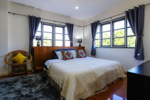 a bedroom with a bed and two windows at Cozy hug home in Ban Phak Wan Noi