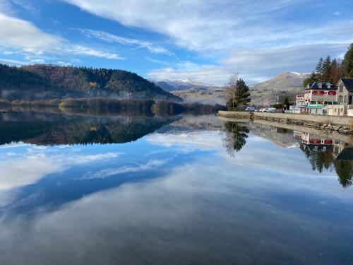 - une vue sur un lac avec des maisons et des montagnes dans l'établissement Hôtel La bonne hôtesse, à Chambon-sur-Lac