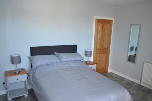 een slaapkamer met een groot wit bed en 2 nachtkastjes bij Sea Breeze Apartment Wick in Wick