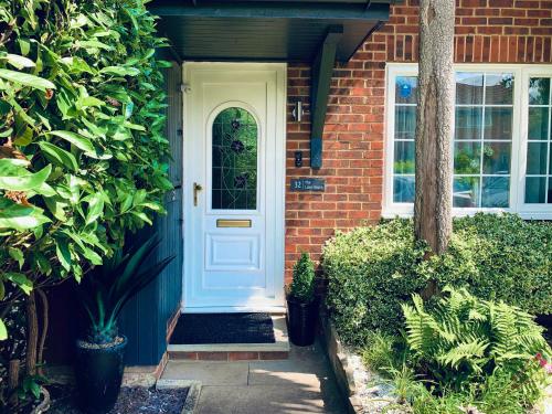 una puerta blanca en una casa de ladrillo con plantas en The Lake House, Woking, en Woking