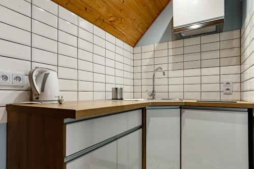 a kitchen with white tiled walls and a wooden ceiling at Dom Wczasowy Radość in Rewal