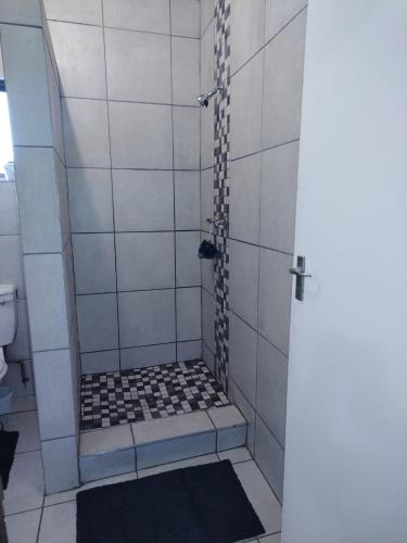 a bathroom with a shower with black and white tiles at Grace Manor in Port Edward
