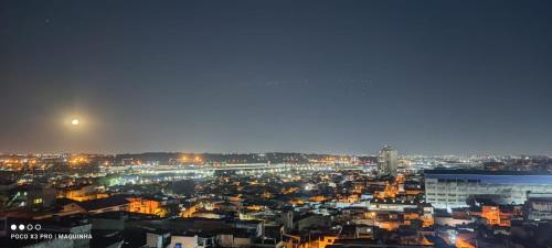 Una ciudad de noche con la luna en el cielo en Lá Casa do Manguinha en Guarulhos