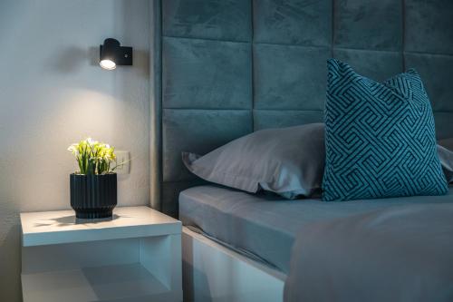 a bed with a blue headboard with a pillow and a table at Apartments Niko in Makarska