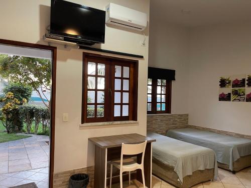 a room with a bed and a table and a tv at Residenza Canoa in Canoa Quebrada