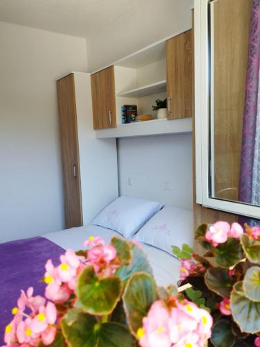 a room with a bed and a mirror and flowers at Apartman, studio and room Kata in Pula