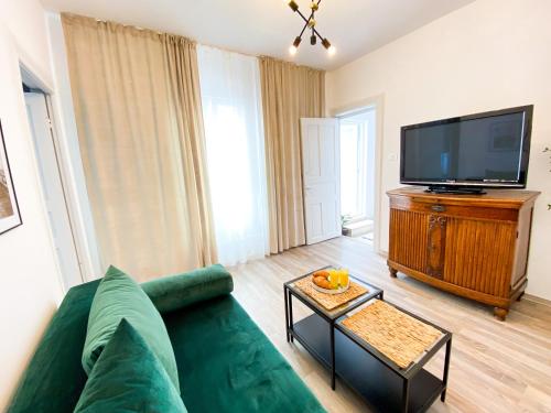 sala de estar con sofá verde y TV de pantalla plana en Villa 56, en Constanţa