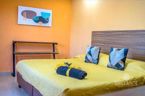 a bedroom with a bed with yellow sheets and blue pillows at Condominio Brillante GDL in Guadalajara