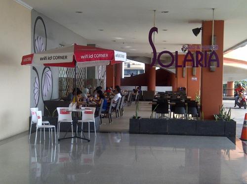 a restaurant with people sitting at tables in a building at Apartemen MTC in Manado