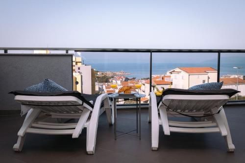 two chairs and a table on a balcony with a view at Apartments Niko in Makarska