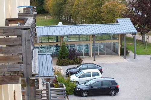 two cars parked in a parking lot in front of a building at Appartement lumineux avec piscine chauffée en saison in Saint-Laurent-du-Jura