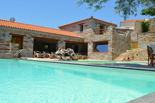 a villa with a swimming pool in front of a house at The House of Prince in Nea Stira