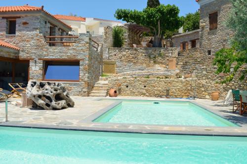 a swimming pool in front of a stone house at The House of Prince in Nea Stira