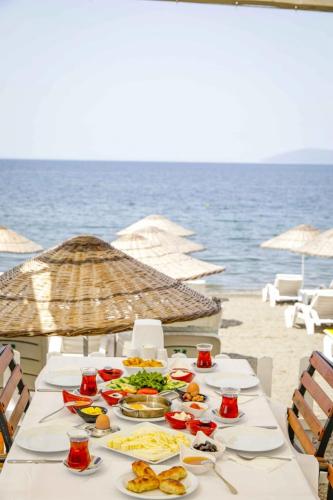 a table with plates of food on the beach at Teos Ormanci Tatil Koyu in Seferihisar