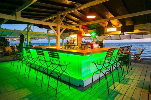 a green bar with chairs on a deck at Teos Ormanci Tatil Koyu in Seferihisar