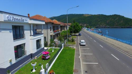a building on the side of a road next to the water at Pensiunea Ionelia in Orşova