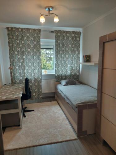 1 dormitorio con cama, escritorio y ventana en Christiana Andersena - apartamenty, en Poznan