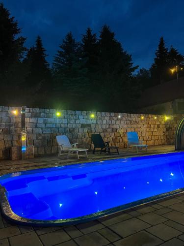 a swimming pool at night with two chairs and a stone wall at Resort LUFT Sněžník in Sněžnik