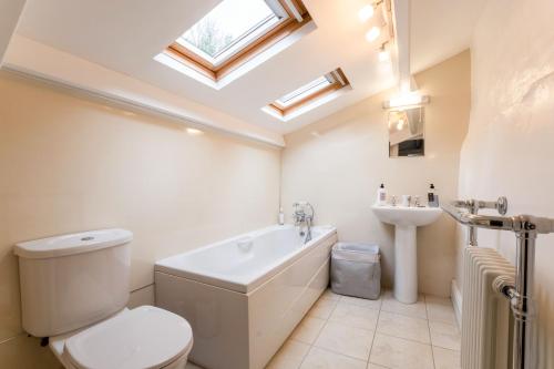 a bathroom with a toilet and a tub and a sink at Peep-O-Day-Stylish 4bedroom cottage with Dale view in Feetham
