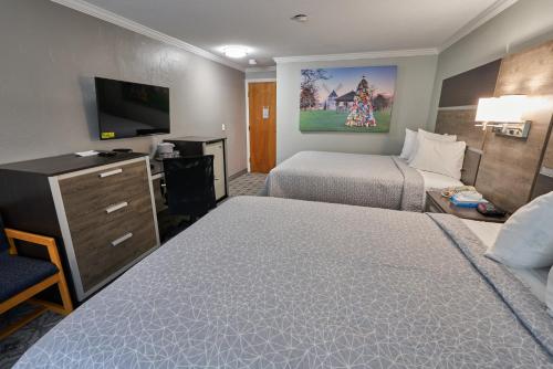 a hotel room with two beds and a flat screen tv at Ambassador Inn and Suites in South Yarmouth