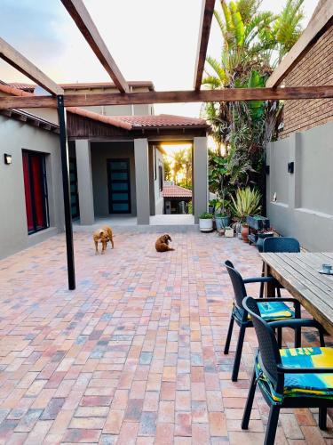 a patio with two dogs and two tables and chairs at Stay at 11 on Gull in Cape Town